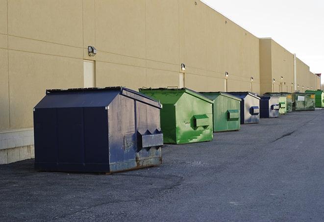 construction workers throw waste into a dumpster behind a building in Biscoe